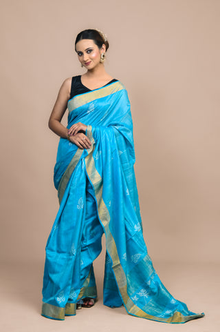Model wearing Kosakari Neelambari sky blue blended Kosa silk hand block printed saree with leaf motifs and golden border.